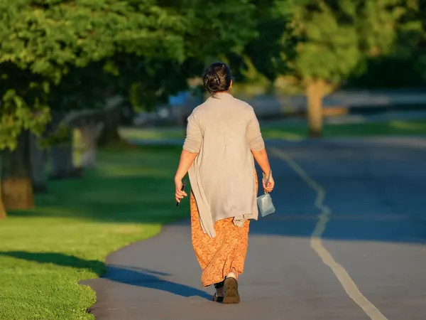 A woman on a morning walk along a tree-lined path