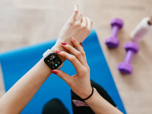 A person checks a smartwatch on a yoga mat