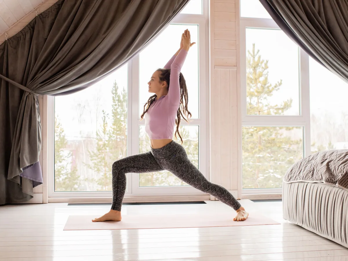 A woman holds a yoga pose in a bright room